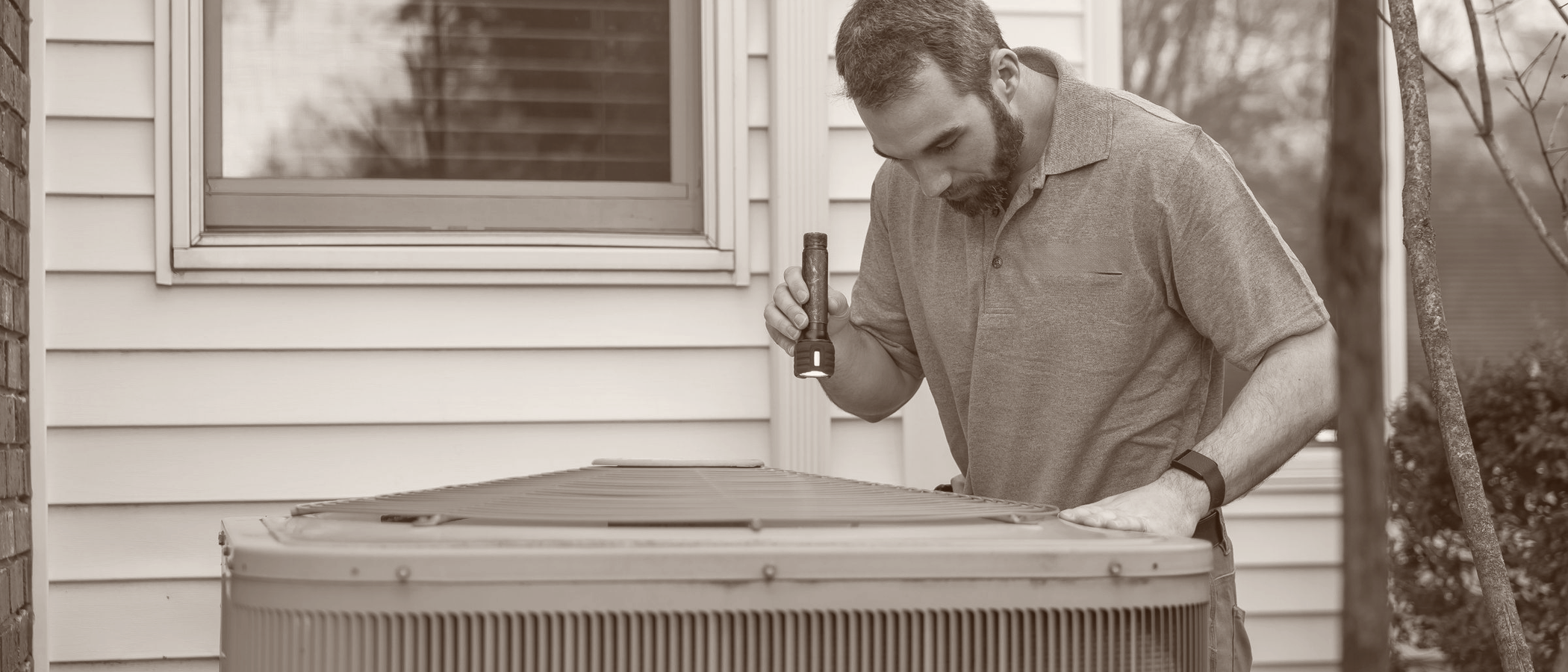 A technician inspecting an outdoor HVAC unit